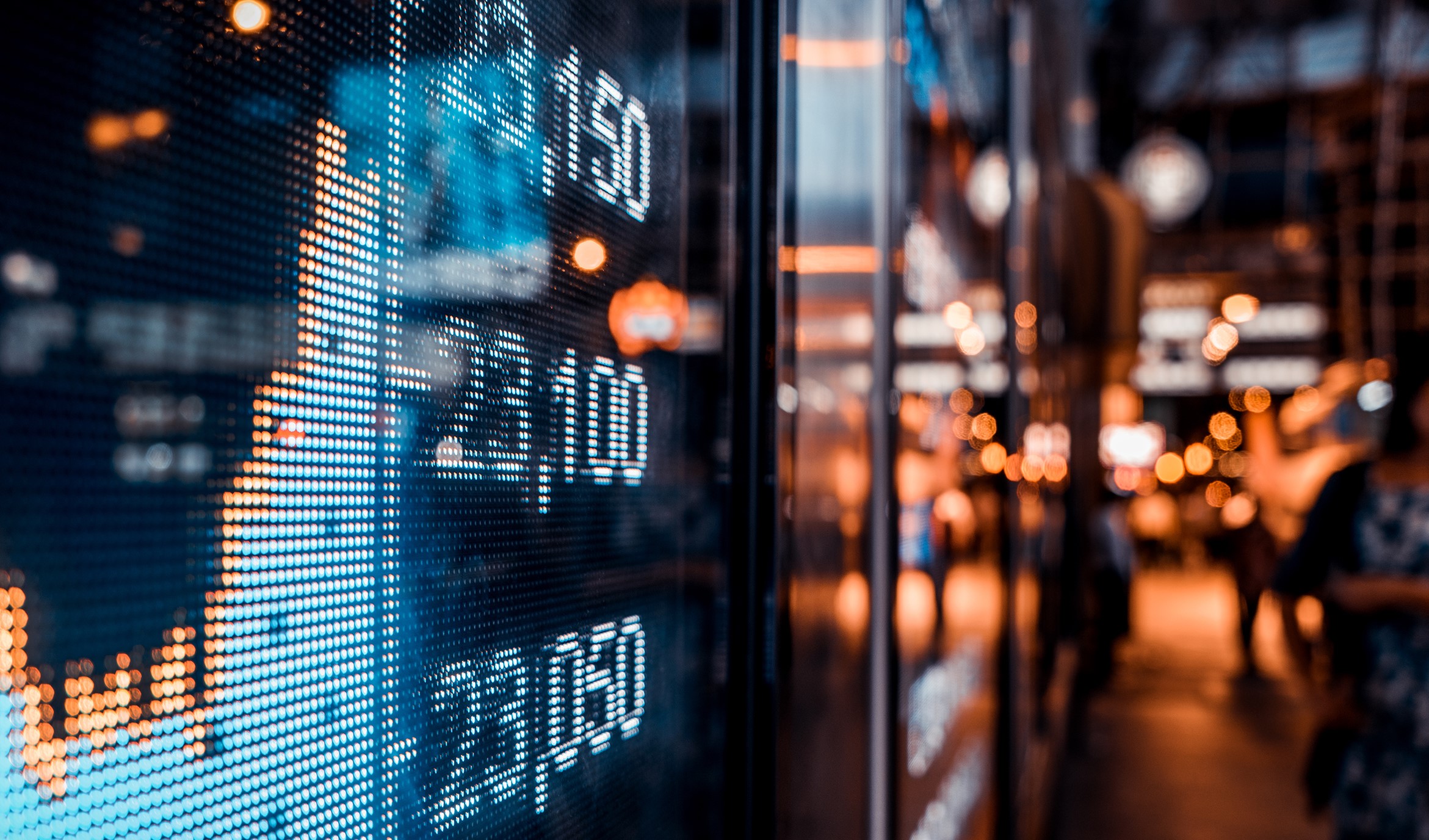 Stock tickers displayed on a busy night in the window of a building in a large city.''